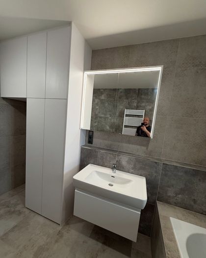 Realizace nábytku do nového domu v Pražských Štěrboholích. Prostor připraven pro pračku se sušičkou a led osvětlená zrcadlová skřínka.